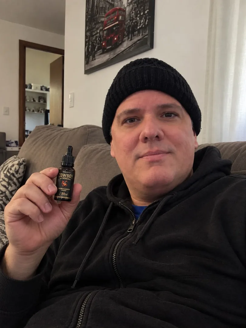 Homem de gorro no sofá, segurando um frasco COWBOY Energia